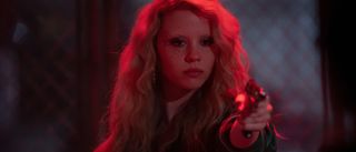 Maxine Minx (Mia Goth) holds up a gun in an alley in MaXXXine